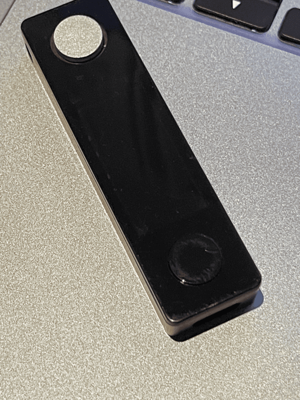 A Ledger Nano hardware wallet on a silver laptop